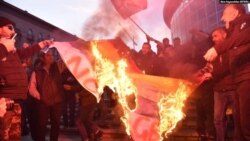 ანტი-გეი დემონსტრანტები ლგბტ დროშას წვავენ. საქართველო.