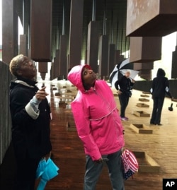 Kim McRae of Laurel, Md., left, and Melodi McNeil of Silver Spring, Md., look at commemorative markers listing lynching victims at the National Memorial for Peace and Justice in Montgomery, Ala., April 26, 2018.