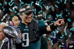 Philadelphia Eagles quarterback Nick Foles (9) holds his daughter, Lily James, after winning the NFL Super Bowl 52 football game against the New England Patriots, Sunday, Feb. 4, 2018, in Minneapolis. The Eagles won 41-33.