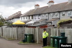 A police officer stands on duty at the back of a property being searched after a man was arrested in connection with an explosion on a London Underground train, in Sunbury-on-Thames, Britain, Sept. 17, 2017.