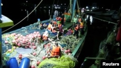 Rescued people in life jackets sit on a fishing boat after a boat they were traveling in capsized off the tourist island of Phuket, Thailand, July 5, 2018.