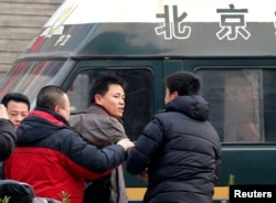 FILE - Zhang Xuezhong (C), a lawyer for Chinese dissident Zhao Changqing, argues with plain-clothed policemen as he refuses to show them his identification card when he was stopped and questioned by them on his way to court to attend Zhao's trial in Beijing, Jan. 23, 2014. The U.N. Human Rights Council has documented 41 disappearance cases in China as of July.