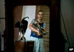 En esta imagen del jueves 4 de abril de 2019, Grettel Montes de Oca Valdés, bailarina profesional y fundadora del grupo Cubanos en Defensa de los Animales, posa con gatos que eran callejeros en su casa de La Habana, Cuba. (AP Foto/Ramón Espinosa)