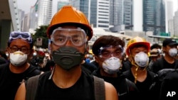 Protesters wearing protection gears march toward the Legislative Council as they continue to protest against the extradition bill in Hong Kong, Monday, June 17, 2019. (AP Photo/Vincent Yu)