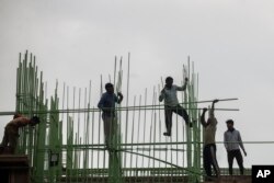 Laborers work at a building site in Mumbai, India, in late November, 2021.