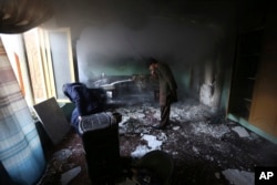 Afghan men inspect the remains of their belongings at the house of parliament member Mir Wali in the aftermath of gunmen's attack late Wednesday in western Kabul, Dec. 22, 2016.