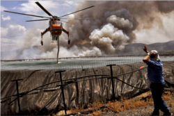 A helicopter gets filled up with water from a tank as a wildfire burns near the village of Spathovouni, near Corinth, Greece July 23, 2021. (Reuters Photo)