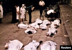 FILE - Medical workers of Beijing's Fuxingmen Hospital look at bodies of protesters killed by soldiers near Tiananmen Square on June 4, 1989.