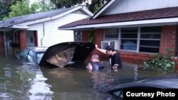 FILE - Andrew Saldivar, left, removes a car battery given to him by a neighbor, which he later installed on a boat to save Houstonians still stranded by the floods. (Photo courtesy of Andrew Saldivar)