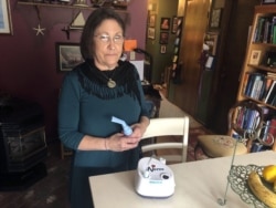 Barbara Trout, who has an asthma disorder, poses next to a machine that helps her breathe at her home in Keizer, Oregon, Wednesday, Oct. 14, 2020. (AP Photo/Andrew Selsky)
