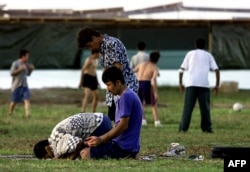 FILE - A small group of Muslim refugees pray at sunset while others play soccer at an Australian-run camp for asylum seekers on the small Pacfic island of Nauru, Sept. 20, 2001. Australia run similar camps on Manus Island in Papua New Guinea.