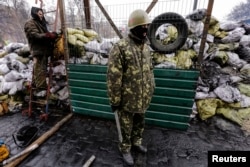 Ukrainian anti-government protesters stand near a passage in a barricade at the site of recent clashes with riot police in Kyiv, Feb. 17, 2014.