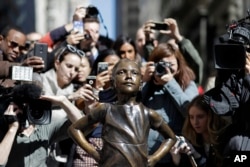 People stop to photograph the "Fearless Girl" statue, Wednesday, March 8, 2017, in New York.