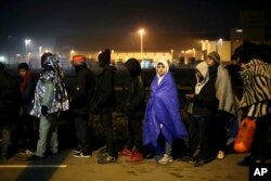 FILE - Migrants wait to register outside a processing center in the makeshift migrant camp known as "the jungle" near Calais, northern France, Oct. 26, 2016.