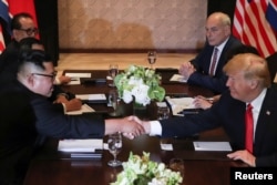 Predsednik SAD Donald Tram i severnokrejski lider Kim Džong Un rukuju se tokom produženog bilateralnog sastanka u hotelu Kapela, na ostrvu Sentosa, Singapur, 12. juna 2018.