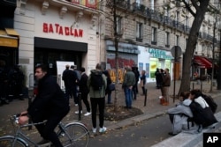 FILE - People stand in front of the entrance of the Bataclan concert hall after a ceremony marking the third anniversary of the Paris attacks of Nov. 2015 in which 130 people were killed, in Paris, Nov. 13, 2018.