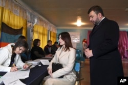 Діючий лідер самопроголошеної "Донецької народної республіки" Денис Пушилін, праворуч, та його дружина чекають, щоб отримати виборчі бюлетені на виборчій дільниці під час сепаратистських виборів у Донецьку, 11 листопада 2018 року.