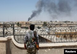A Kurdish fighter from the People's Protection Units looks at the damage after a coalition airstrike in Raqqa, Syria, June 16, 2017.