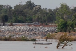 FILE - A fishing boat passes near a construction site of the Don Sahong dam, near the Cambodia-Laos border, June 20, 2016.