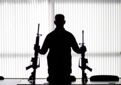 FILE - An agent of the U.S. Bureau of Alcohol, Tobacco, Firearms and Explosives holds guns at an ATF field office in Glendale, Calif., Aug. 29, 2017.