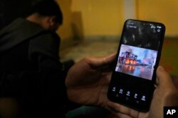 ผู้ชี้ภัยชาวเมียนมาที่หนีเหตุความรุนแรงจากรัฐชิน ทางตะวันตกเฉียงเหนือของเมียนมา กำลังดูภาพและคลิปวิดีโอบ้านเรือนที่ถูกเผามอดไหม้ เมื่อ 13 ธ.ค. 2564