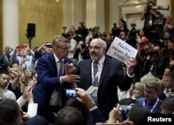 Agentes de seguridad retiran a un hombre que sostiene un cartel antes de la conferencia de prensa conjunta del presidente de los Estados Unidos, Donald Trump, y el presidente de la Federación de Rusia, Vladimir Putin, en el palacio presidencial de Helsinki, Finlandia, el 16 de julio de 2018.