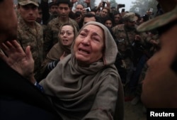 FILE - Grandmother, right, and mother of Muhammad Ali Khan, a student who was killed during an attack by Taliban gunmen on Army Public School, react during a visit by Imran Khan, left, chairman of Pakistan Tehrik-e-Insaf (PTI) political party, at the school in Peshawar.
