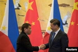 FILE - Philippine President Rodrigo Duterte, left, and Chinese President Xi Jinping shake hands after a signing ceremony in Beijing, Oct. 20, 2016.