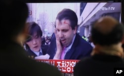 FILE - South Korean men watch a TV news program reporting U.S. Ambassador to South Korea Mark Lippert injured in a knife attack at Seoul railway station in Seoul, South Korea, March 5, 2015.
