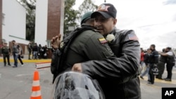 FILE - A man embraces a police officer, outside the General Francisco de Paula Santander Police Academy, a day after a car bomb exploded at the site, in Bogota, Colombia, Jan. 18, 2019.