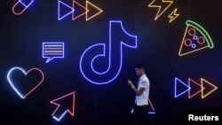 一名男子手持手持走過TikTok的標識。（2019年10月18日）