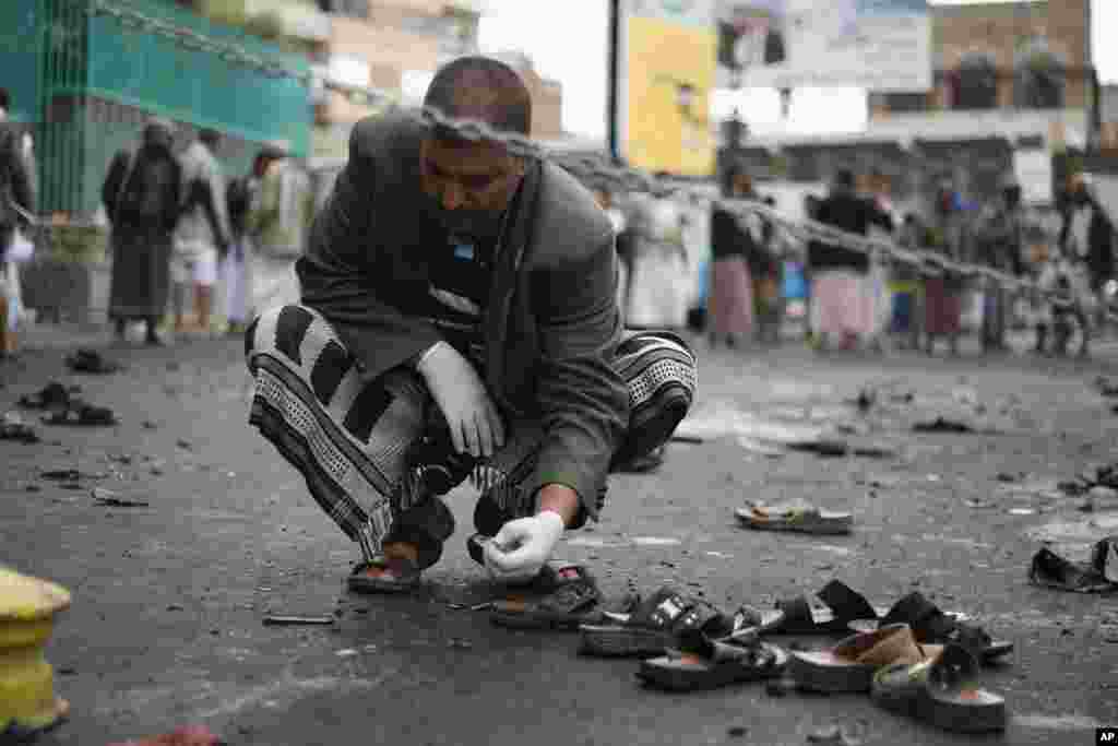A Yemeni security official inspects objects near the site of a suicide bombing in Sana'a, Oct. 9, 2014. 