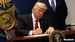 FILE - U.S. President Donald Trump signs an executive order to impose tighter vetting of travelers entering the United States, at the Pentagon in Washington, Jan. 27, 2017. 