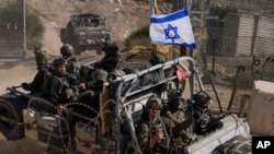 以色列士兵乘坐掛有以色列國旗的軍車穿過敘利亞和被以色列控制的戈蘭高地之間的阿爾法線附近的安全欄。 （2024年12月12日）