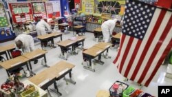 FILE - In this Nov. 5, 2020, file photo, custodial workers clean a classroom at Richard A. Simpson Elementary School in Arnold, Mo. The school went to fully virtual learning on Monday, Nov. 2, after more than 5% of the staff and students tested positive f