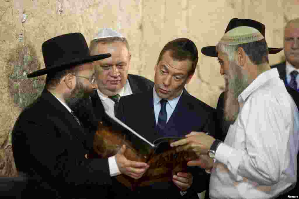 Russia's Prime Minister Dmitry Medvedev (C) looks at a book presented to him during a visit to the Western Wall in Jerusalem.