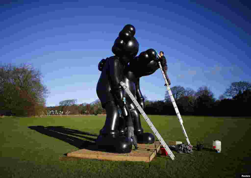 Workers clean a sculpture entitled "Along The Way" by American artist Kaws at the Yorkshire Sculpture Park in Wakefield, Britain.