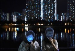 Protesters wear masks of Chinese President Xi Jinping, right, and Hong Kong Chief Executive Carrie Lam during a protest in Hong Kong, Oct. 18, 2019.