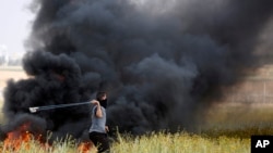 Mpalestina akitupa mawe kuelekea upande wa wanajeshi wa Israeli wakati wa mapambano kati ya waandamanaji wa Palestina na majeshi ya Israeli, huko ukanda wa Gaza Machi 30, 2018