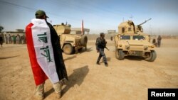 FILE - A soldier wraps himself with an Iraqi flag after the liberation of Khalidiya village from Islamic State militants, on the southern outskirts of Mosul, Iraq, Oct. 20, 2016. 