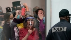 FILE - In this Nov. 4, 2020, photo, election challengers in Detroit yell as they look through the windows of the central counting board as police were helping to keep additional challengers from entering due to overcrowding.