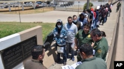 FILE - U.S. Border Patrol officers return a group of migrants back to the Mexico side of the border, as Mexican immigration officials check a list, in Nuevo Laredo, Mexico, July 25, 2019.