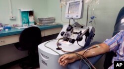 A recovered COVID-19 patient donates blood at the Arnulfo Arias Madrid Hospital, in Panama City, Wednesday, May 13, 2020. The blood from recovered COVID-19 patients may have antibodies that can help those critically ill from the virus. (AP Photo/Arnulfo Franco)