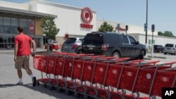 FILE - A Target employee returns shopping carts from the parking lot, in Omaha, Neb., June 16, 2020. 