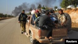 Combatientes rebeldes viajan junto a civiles que huyen de áreas de conflicto en Dahiyet al-Assad, en el oeste de Alepo, Siria.