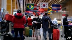  Travelers wait in line to check in for flights at Logan Airport, Tuesday, Dec. 21, 2021, in Boston.