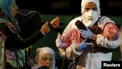 Rescue worker carries a child arriving with other survivors on the migrant boat at the Sicilian harbor of Pozzallo April 19, 2015. (REUTERS/Alessandro Bianchi)