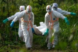 Burial workers dressed in protective gear carry the remains of an Ebola victim in Beni, Congo, July 14, 2019.