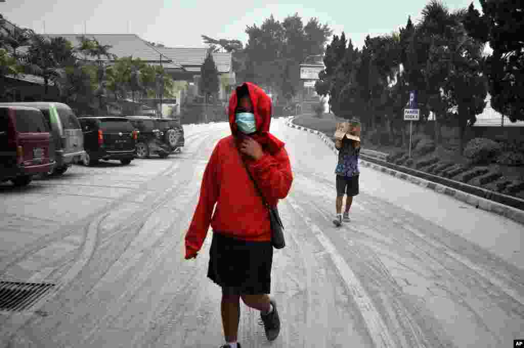 Indonesian students walk on a street covered with volcanic ash following an eruption of Mount Kelud, in Yogyakarta, Indonesia, Feb. 14, 2014. 