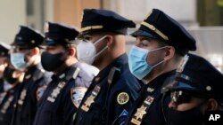 FILE - New York Police Department officers wearing masks stand during a service at St. Patrick's Cathedral in New York City to honor colleagues who have died due to COVID-19, Oct. 5, 2020.